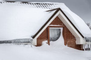 The roof of a house is covered in snow and ice after a winter storm